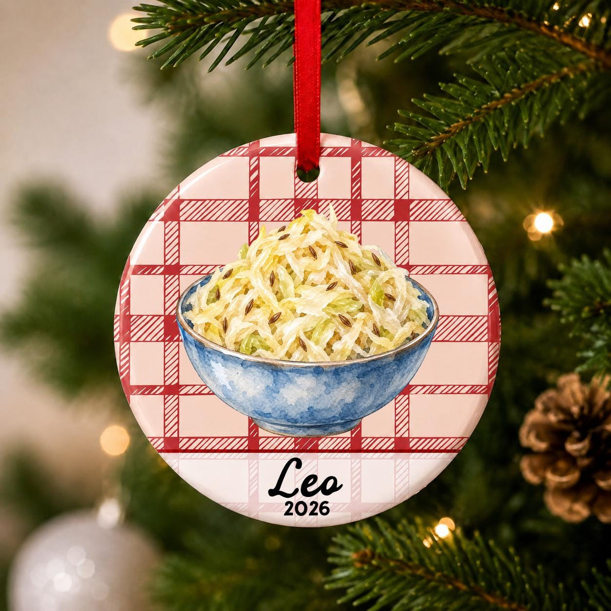 Close-up of the personalized sauerkraut ceramic ornament with name and year on red plaid hanging on a Christmas tree