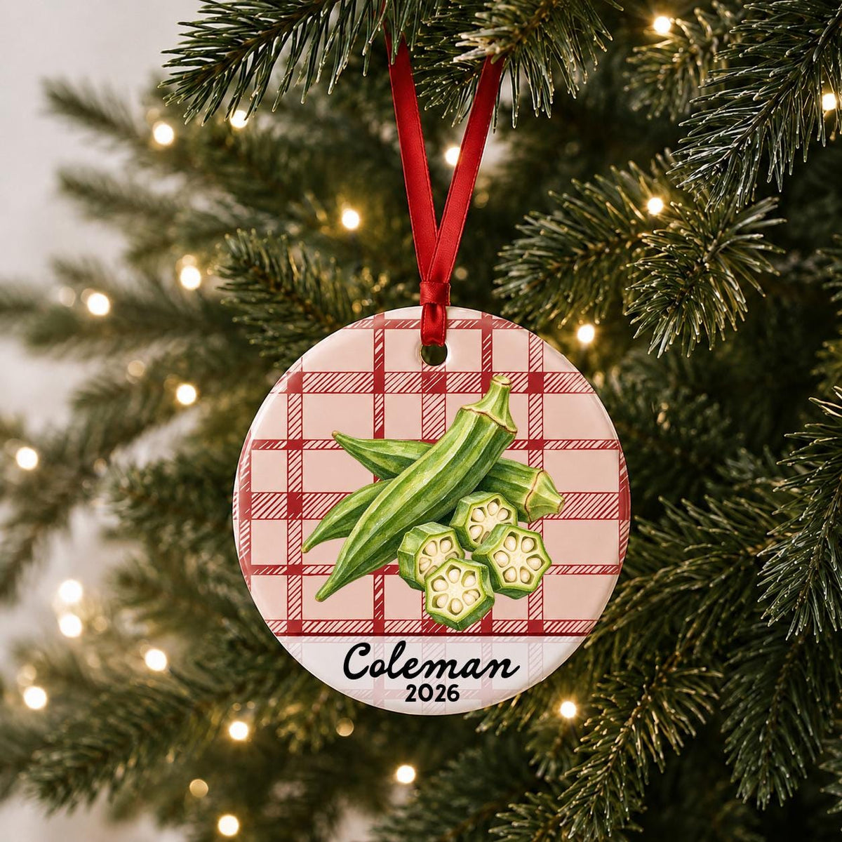 Personalized okra ceramic ornament with name and year on red plaid hanging on a lit Christmas tree