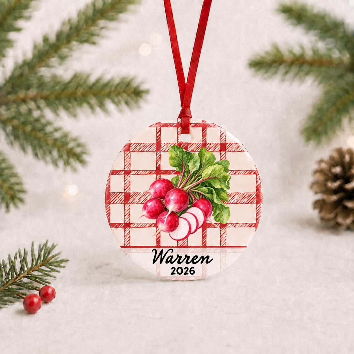 Personalized radishes ceramic ornament with name and year on red plaid with red ribbon on a white surface with pine branches and pinecones