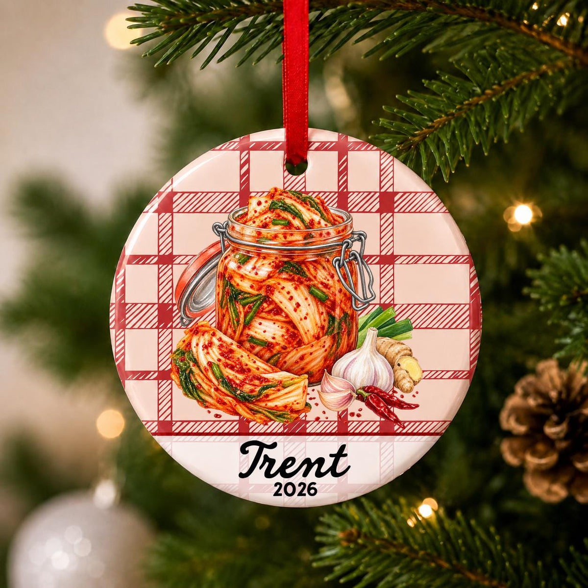 Close-up of the personalized kimchi ceramic ornament with name and year on red plaid hanging on a Christmas tree