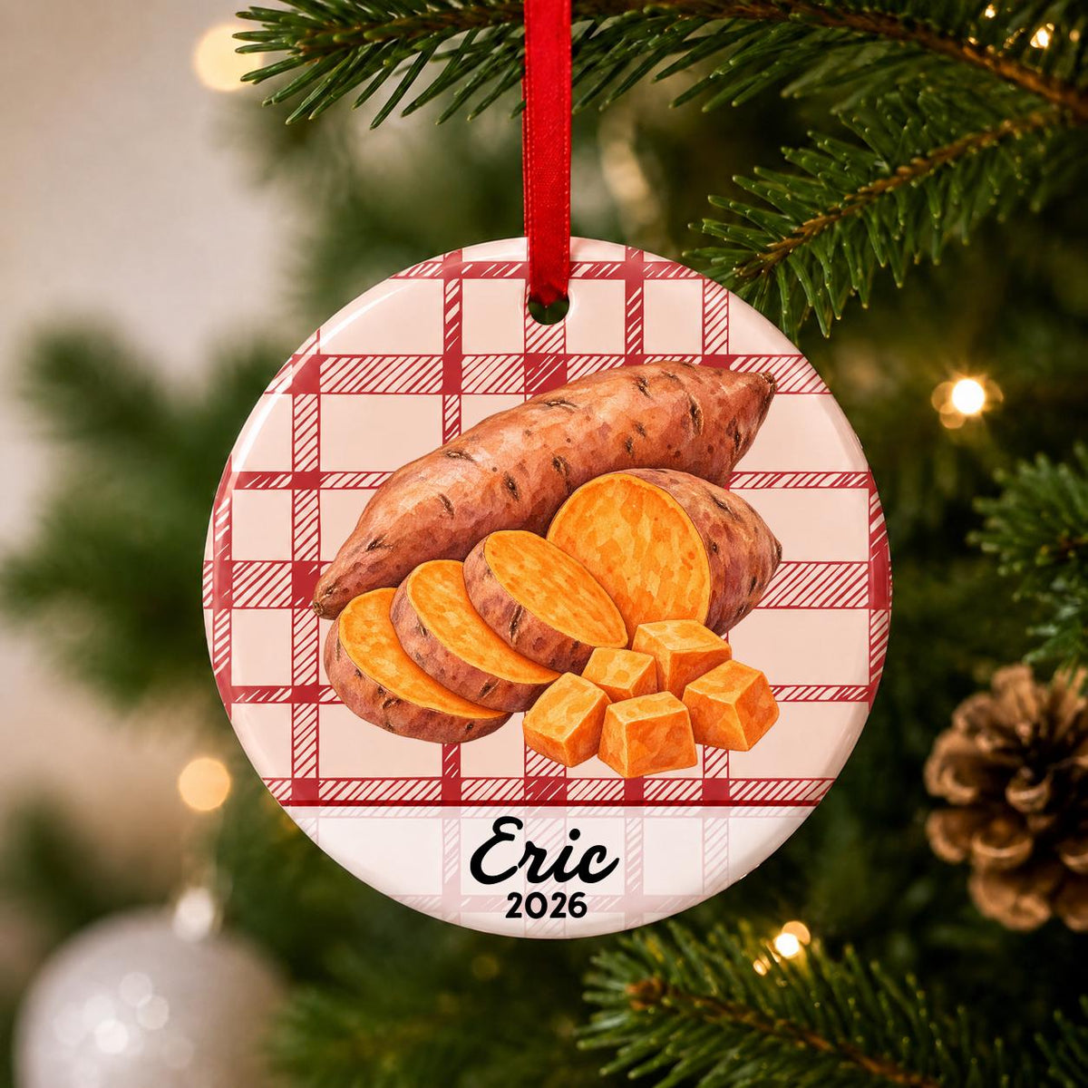 Close-up of the personalized sweet potato ceramic ornament with name and year on red plaid hanging on a Christmas tree