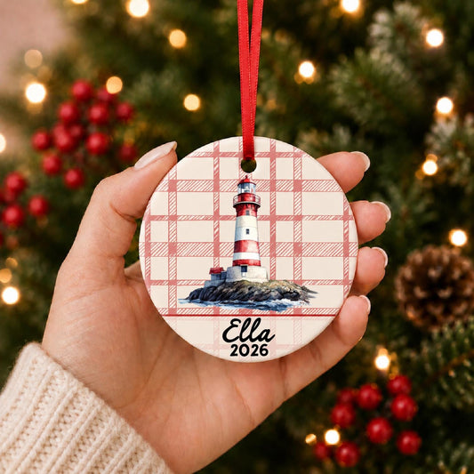 Hand holding the personalized island lighthouse ceramic ornament with name and year on red plaid in front of a Christmas tree