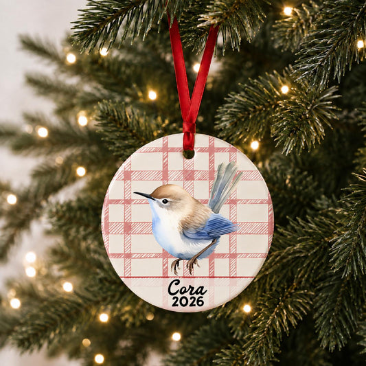 Personalized wren ceramic ornament with name and year on red plaid hanging on a lit Christmas tree