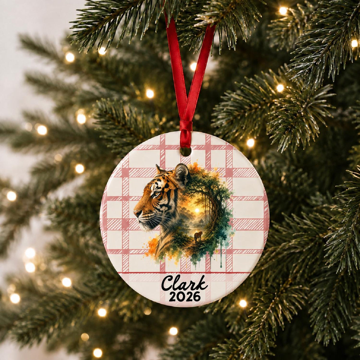 Personalized tiger ceramic ornament with name and year on red plaid hanging on a lit Christmas tree