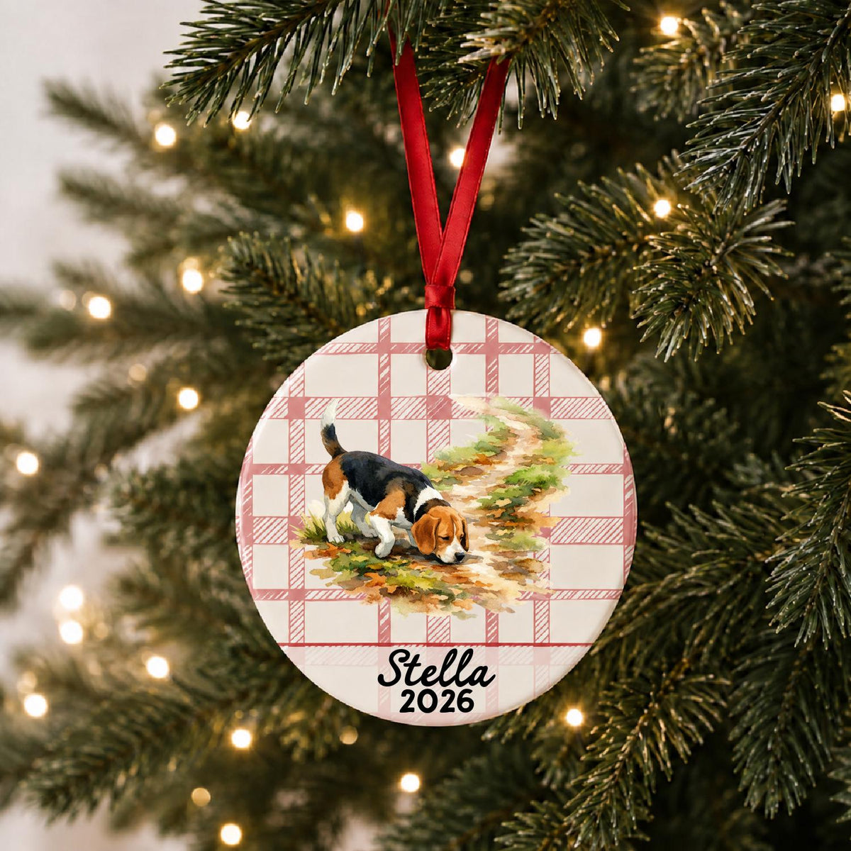 Personalized beagle ceramic ornament with name and year on red plaid hanging on a lit Christmas tree