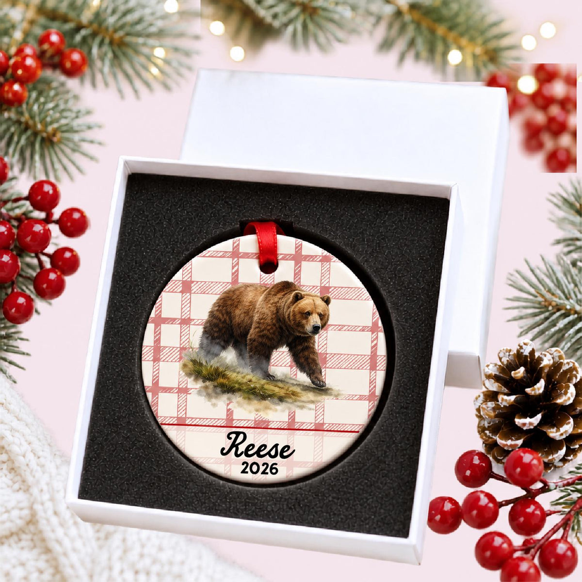 Personalized brown bear ceramic ornament with name and year on red plaid in a white gift box with protective foam