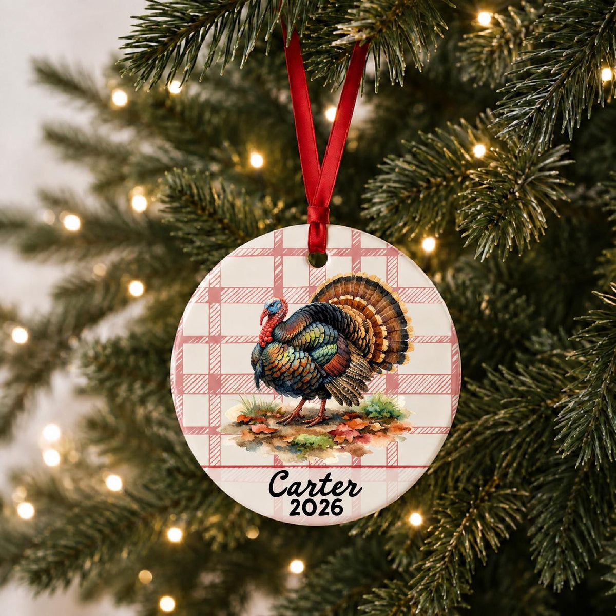 Personalized wild turkey ceramic ornament with name and year on red plaid hanging on a lit Christmas tree