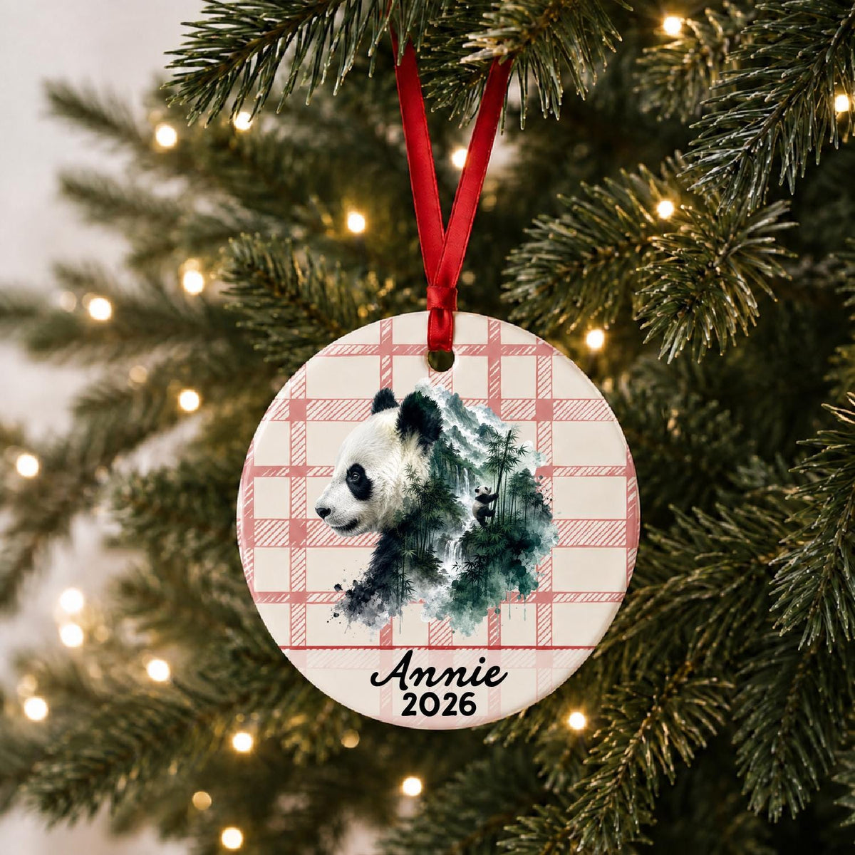 Personalized giant panda ceramic ornament with name and year on red plaid hanging on a lit Christmas tree