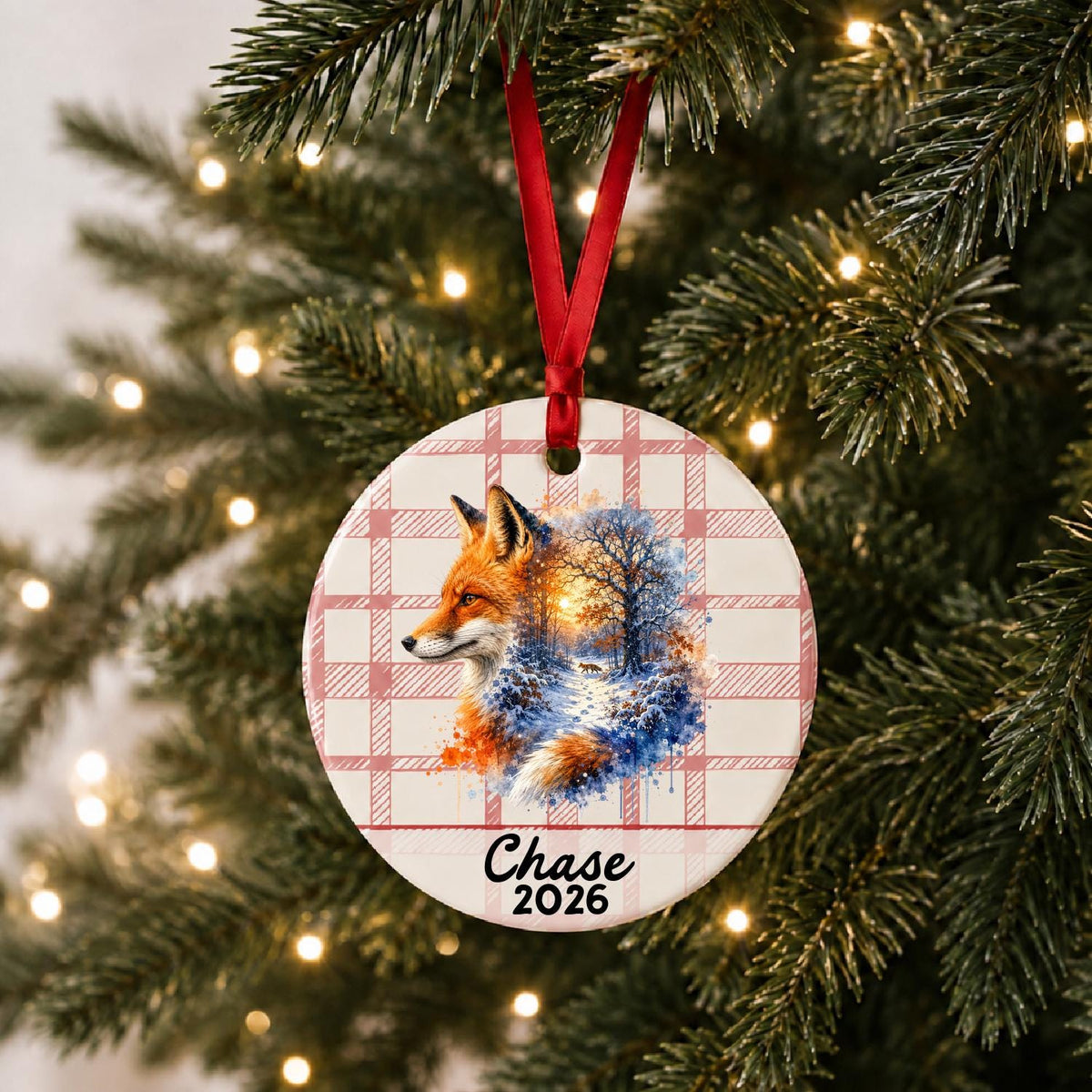 Personalized red fox ceramic ornament with name and year on red plaid hanging on a lit Christmas tree