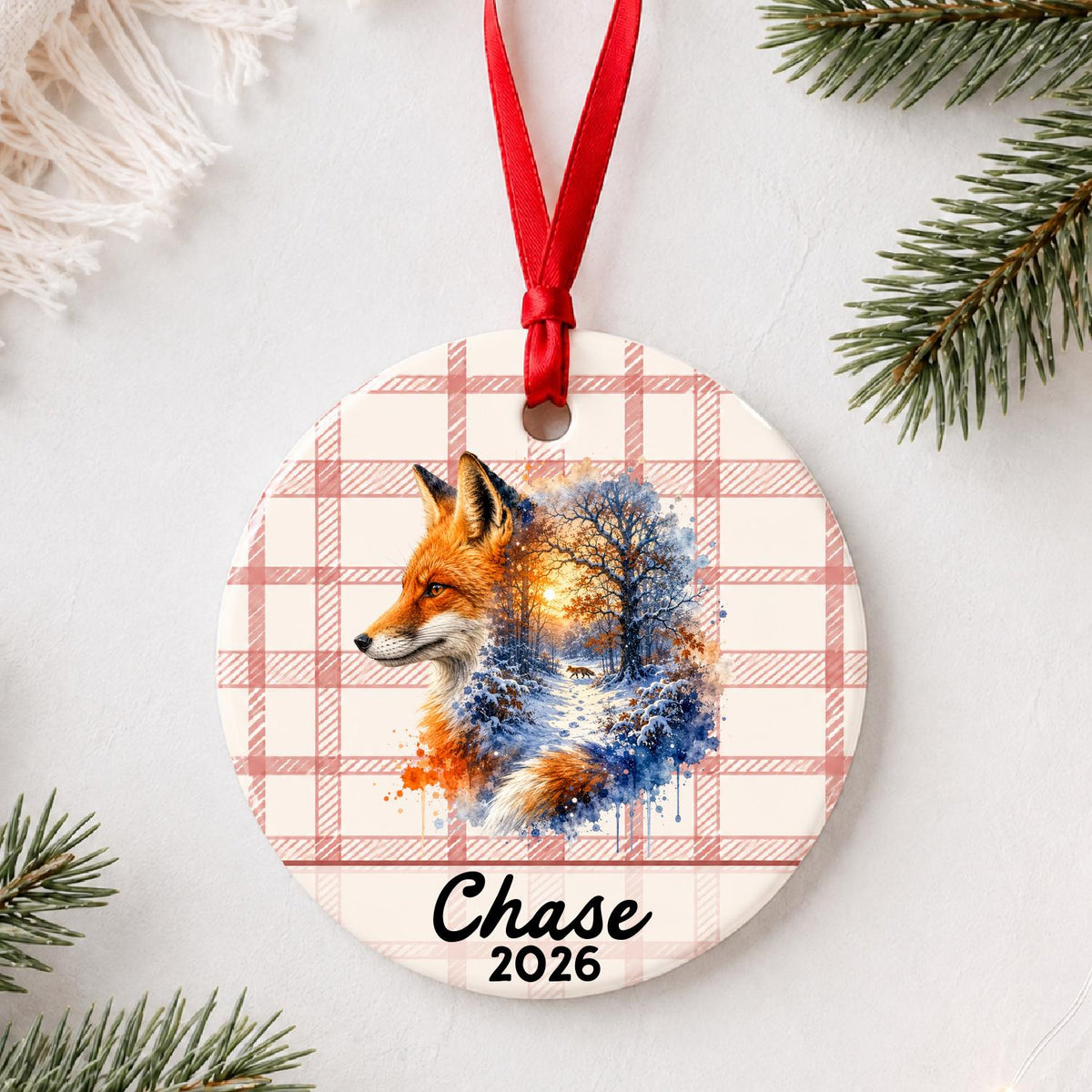 Personalized red fox ceramic ornament with name and year on red plaid styled with pine branches on a soft white background