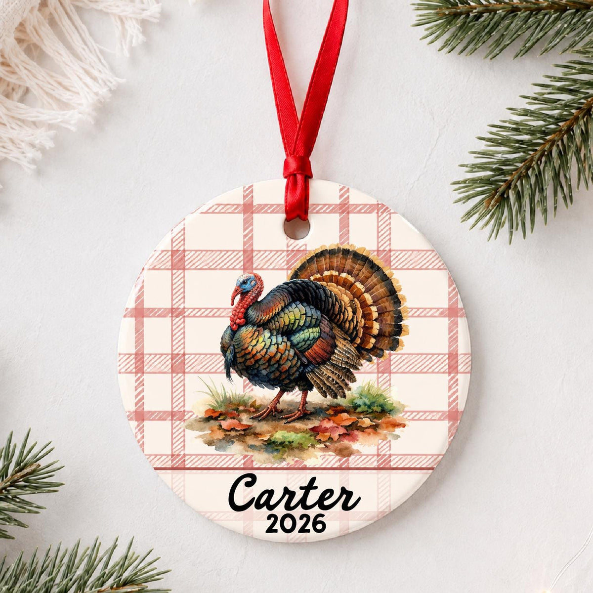 Personalized wild turkey ceramic ornament with name and year on red plaid styled with pine branches on a soft white background