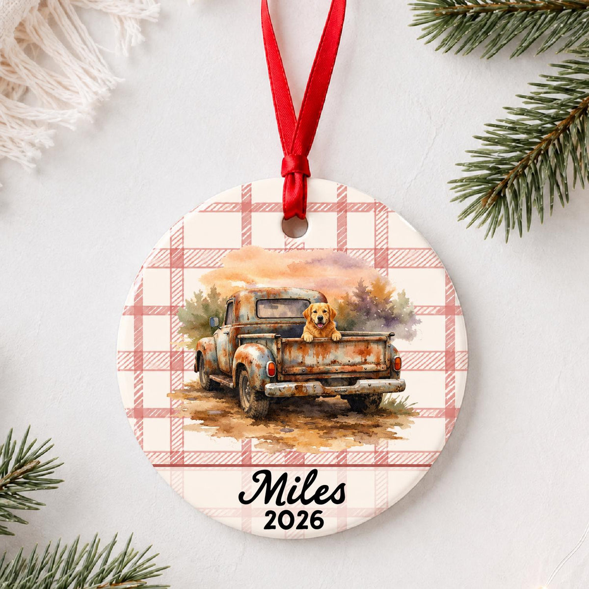 Personalized vintage truck and dog ceramic ornament with name and year on red plaid styled with pine branches on a soft white background