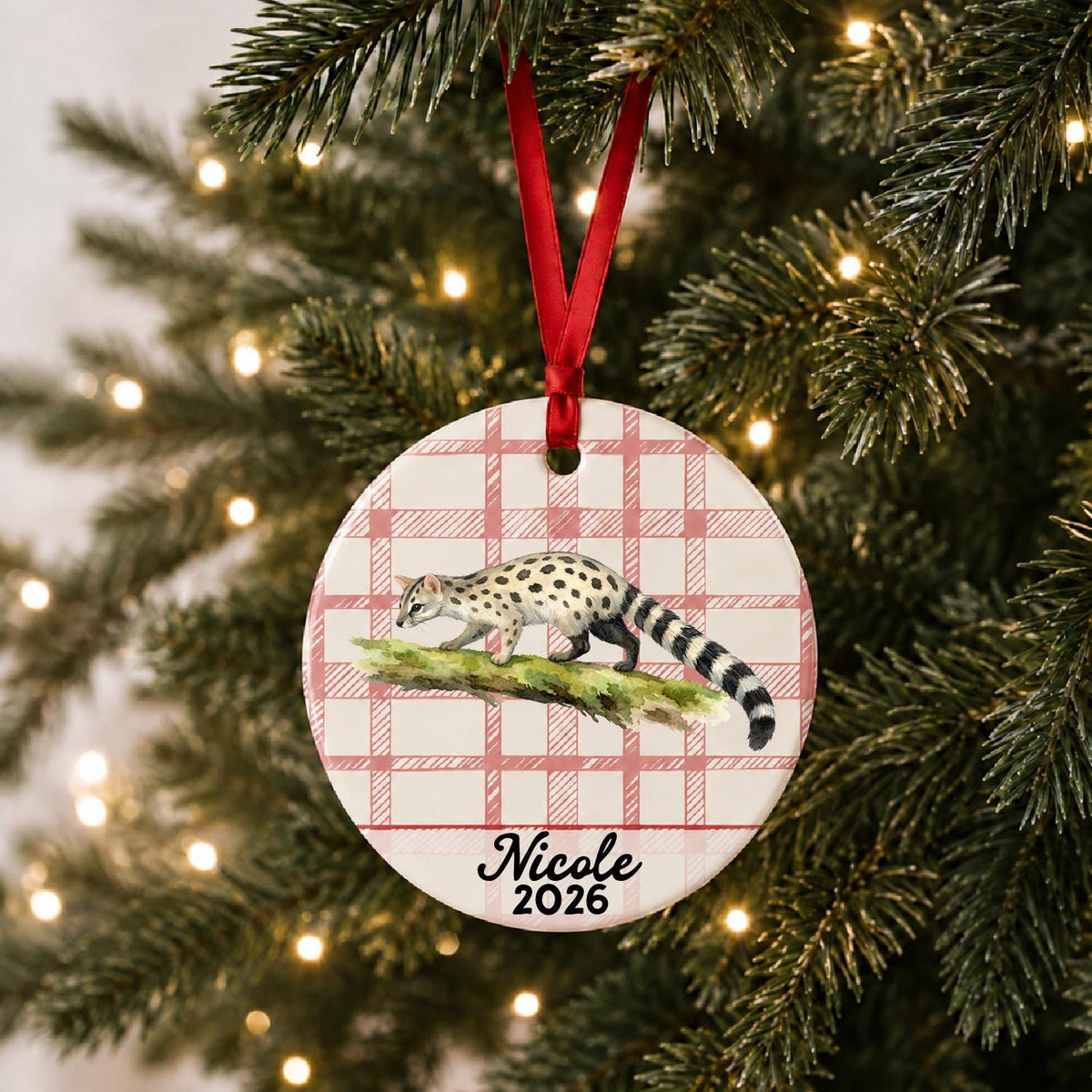 Personalized genet ceramic ornament with name and year on red plaid hanging on a lit Christmas tree