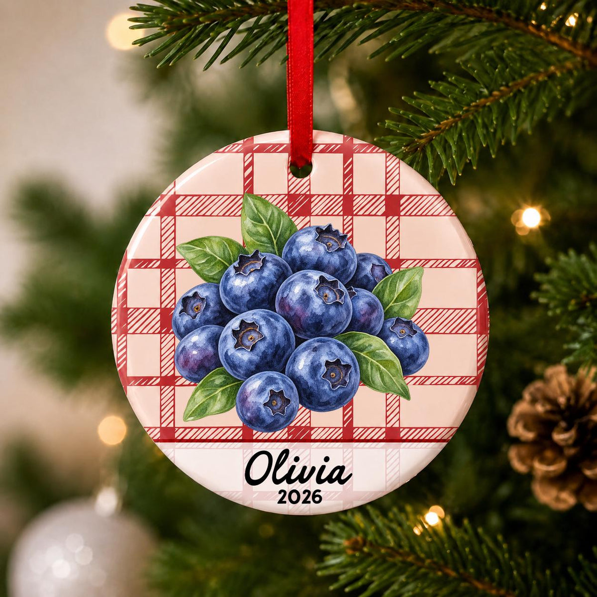Close-up of the personalized blueberries ceramic ornament with name and year on red plaid hanging on a Christmas tree