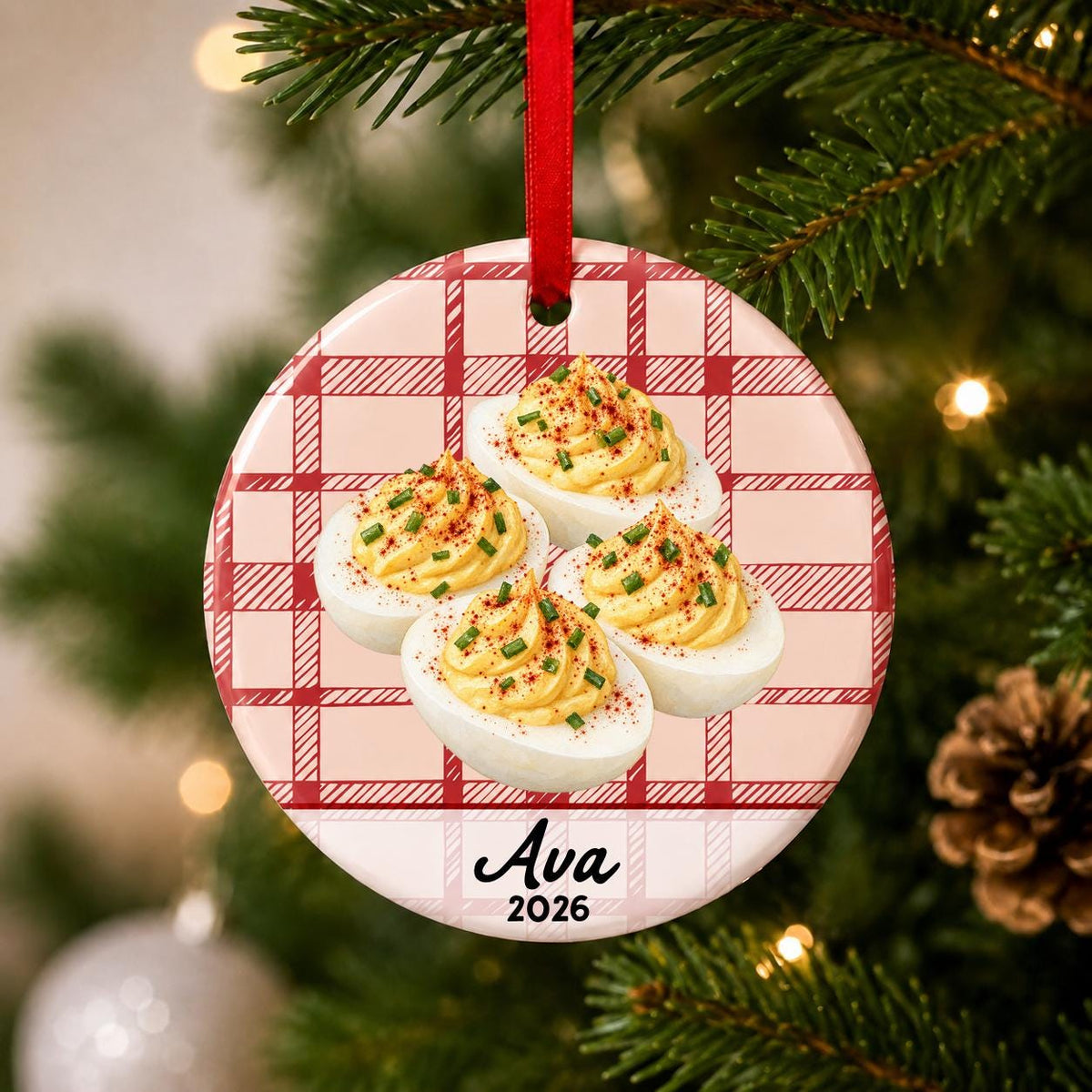 Close-up of the personalized deviled eggs ceramic ornament with name and year on red plaid hanging on a Christmas tree