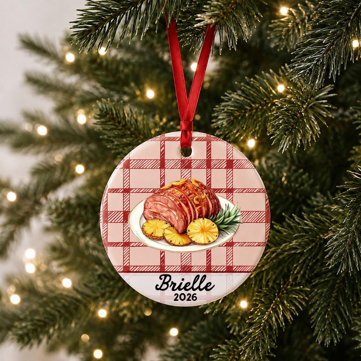 Personalized Christmas ham ceramic ornament with name and year on red plaid hanging on a lit Christmas tree