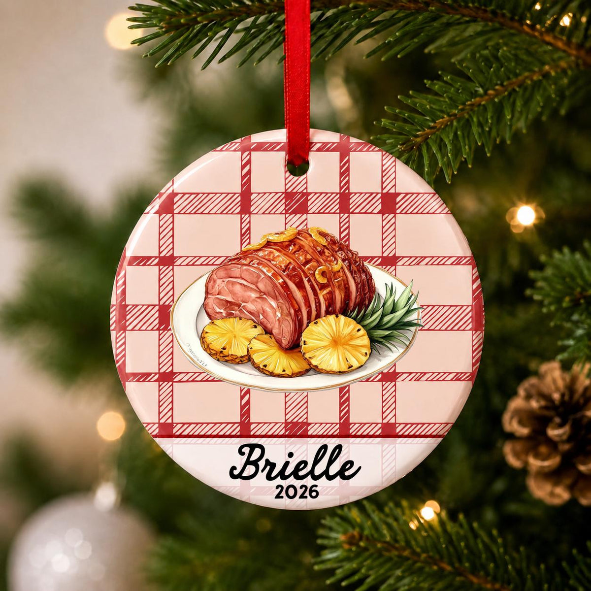 Close-up of the personalized Christmas ham ceramic ornament with name and year on red plaid hanging on a Christmas tree