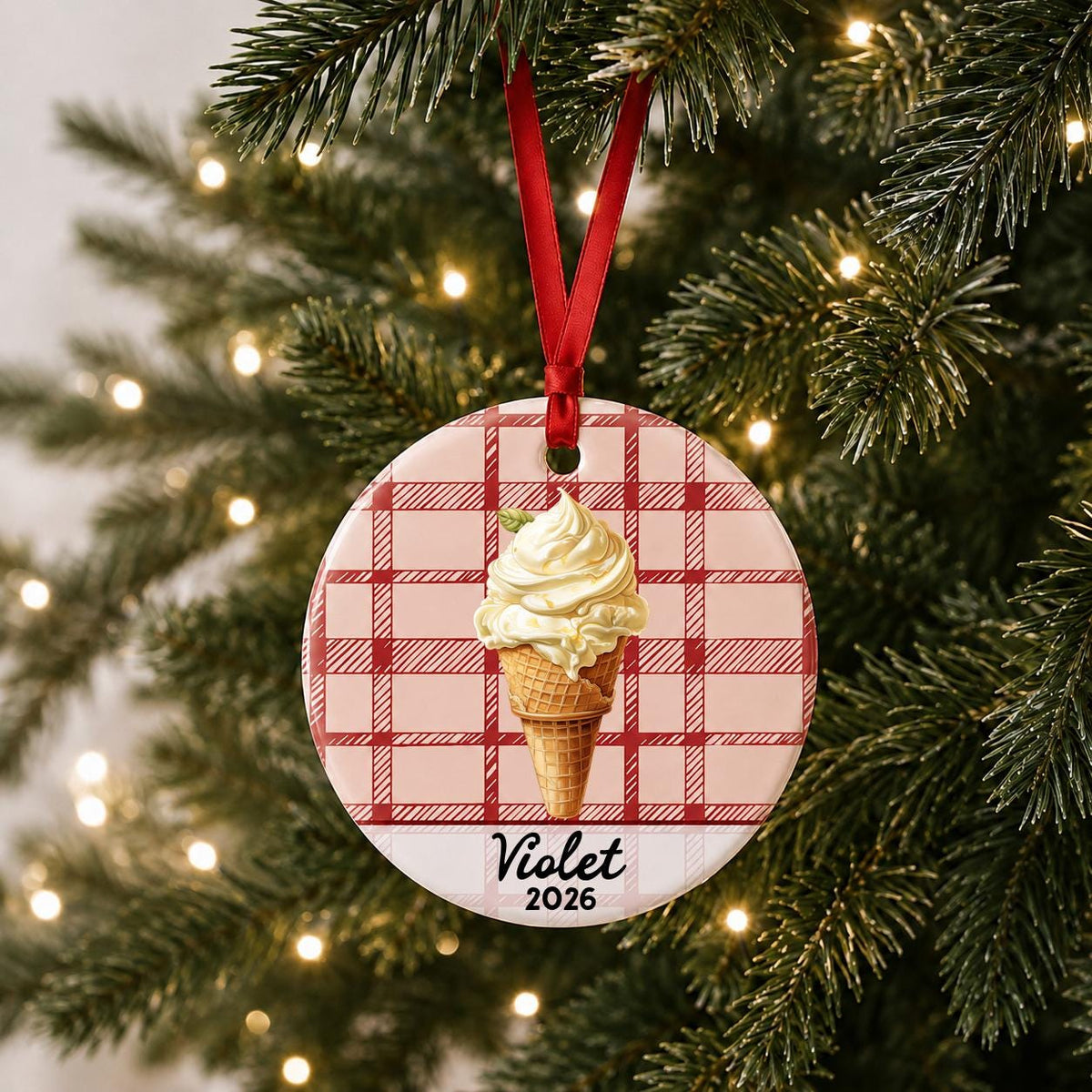 Personalized soft serve ice cream ceramic ornament with name and year on red plaid hanging on a lit Christmas tree