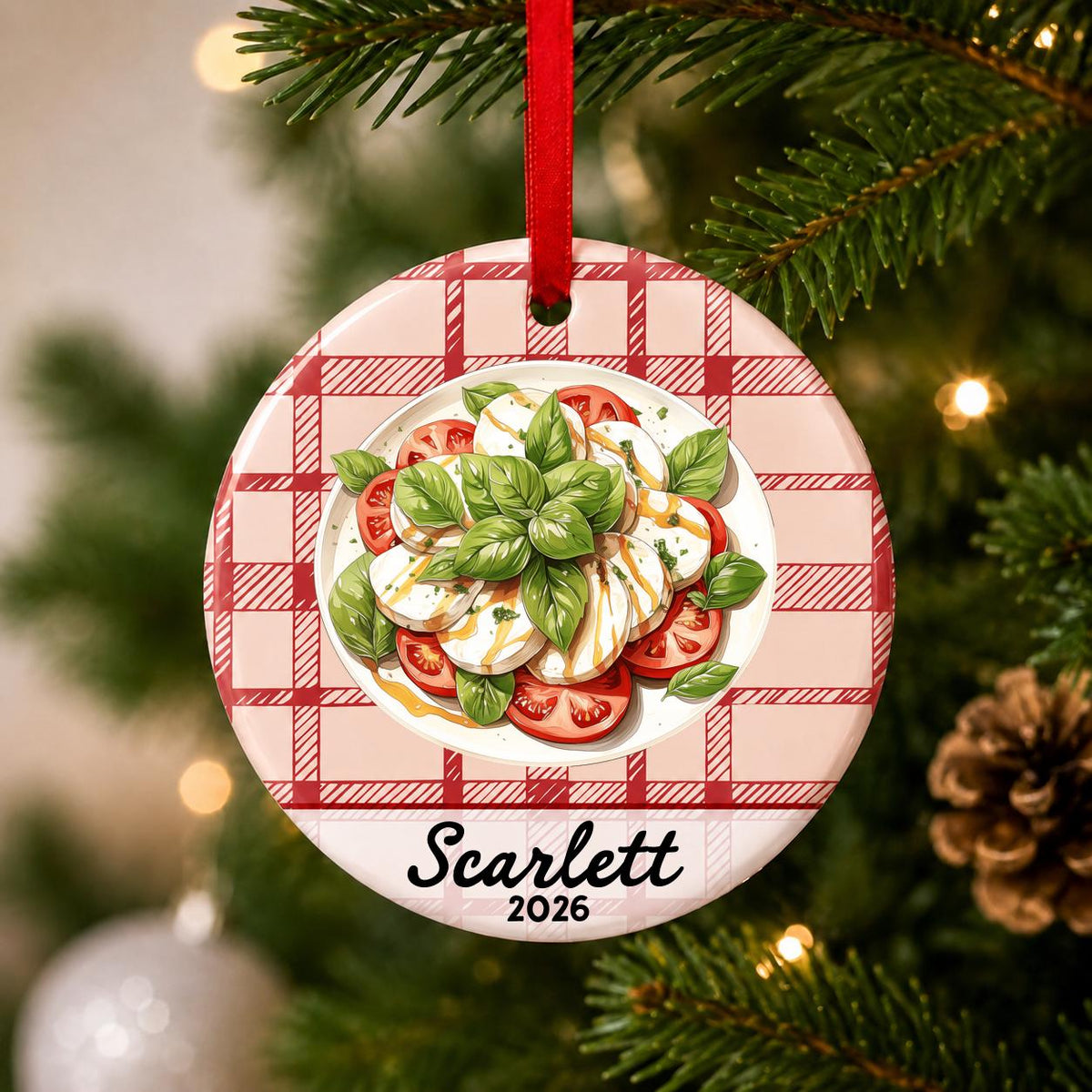 Close-up of the personalized caprese salad ceramic ornament with name and year on red plaid hanging on a Christmas tree