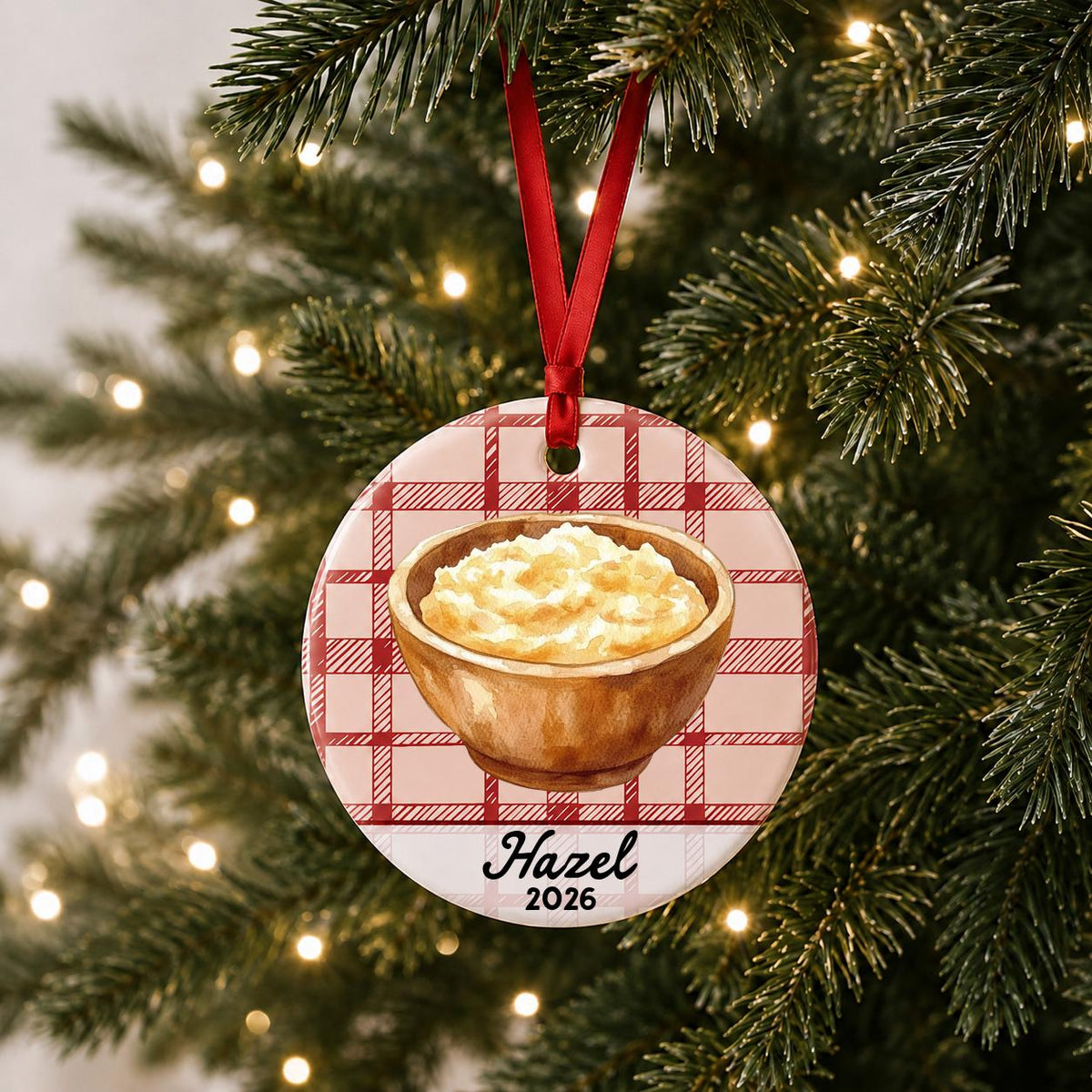 Personalized mashed potatoes ceramic ornament with name and year on red plaid hanging on a lit Christmas tree