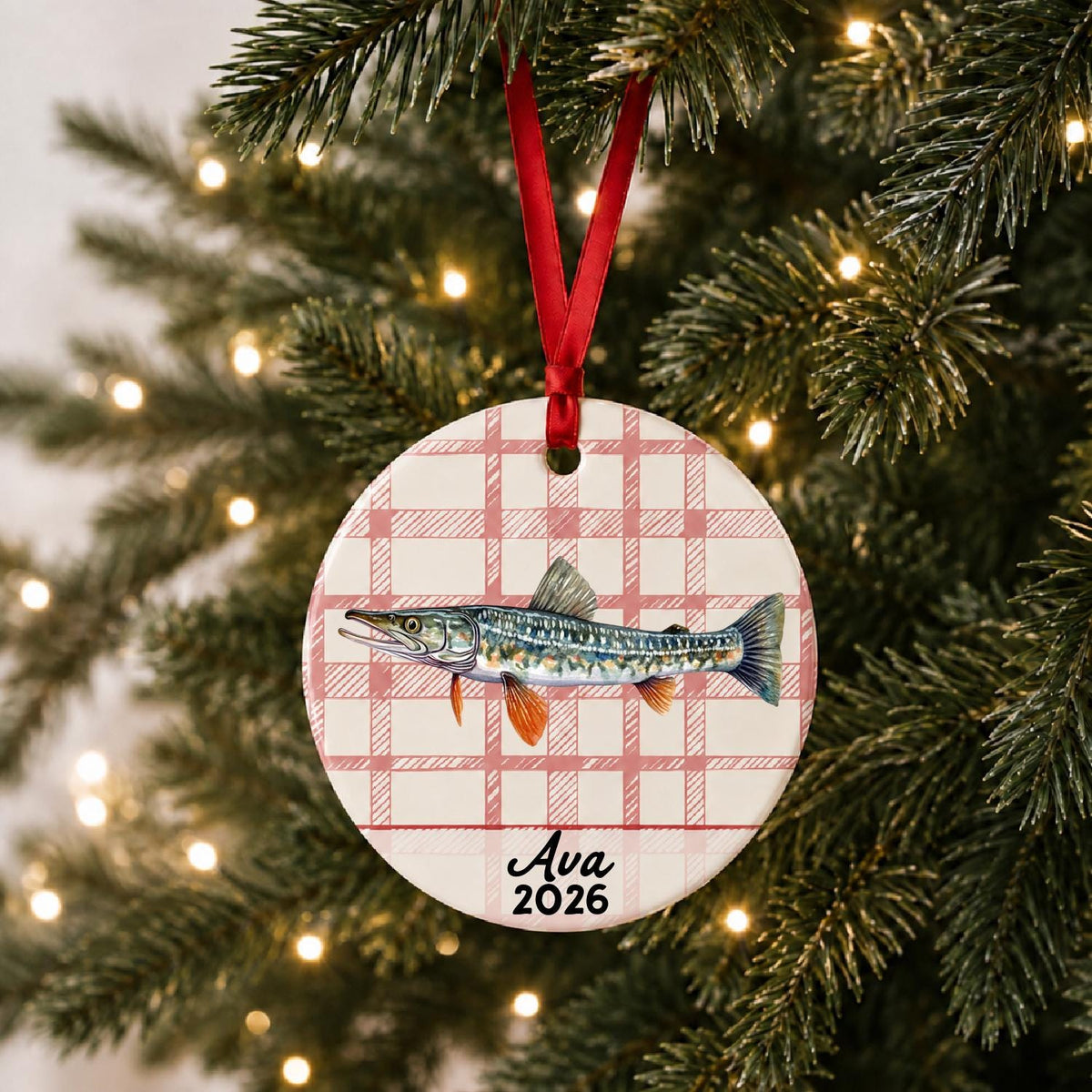 Personalized northern pike ceramic ornament with name and year on red plaid hanging on a lit Christmas tree
