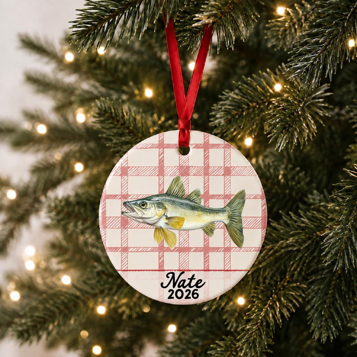 Personalized walleye ceramic ornament with name and year on red plaid hanging on a lit Christmas tree
