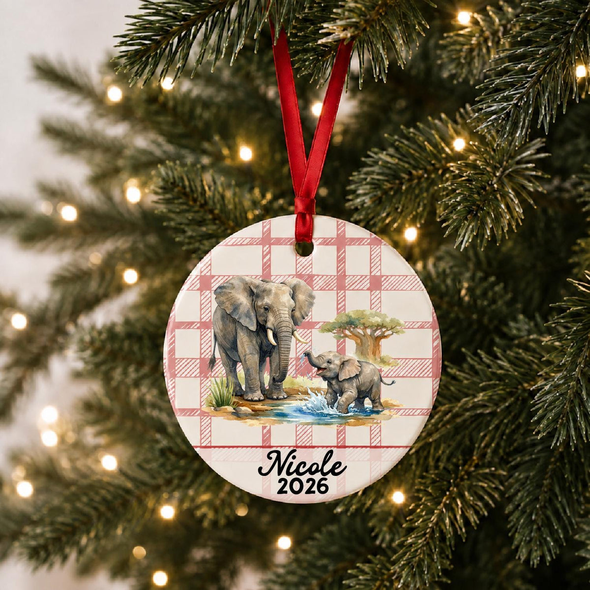 Personalized African elephant ceramic ornament with name and year on red plaid hanging on a lit Christmas tree