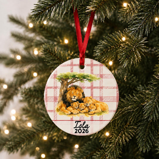 Personalized lion pride ceramic ornament with name and year on red plaid hanging on a lit Christmas tree
