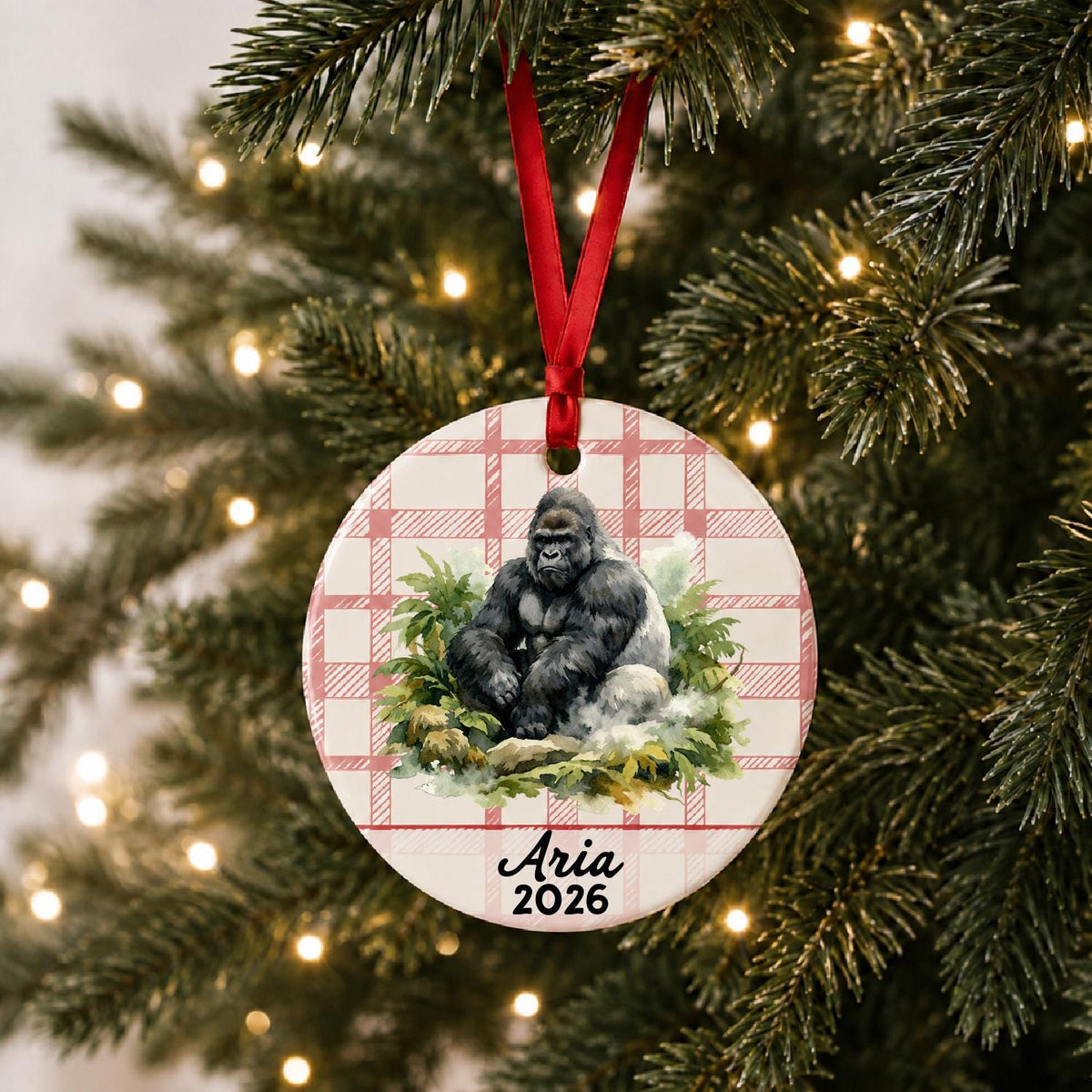 Personalized silverback gorilla ceramic ornament with name and year on red plaid hanging on a lit Christmas tree