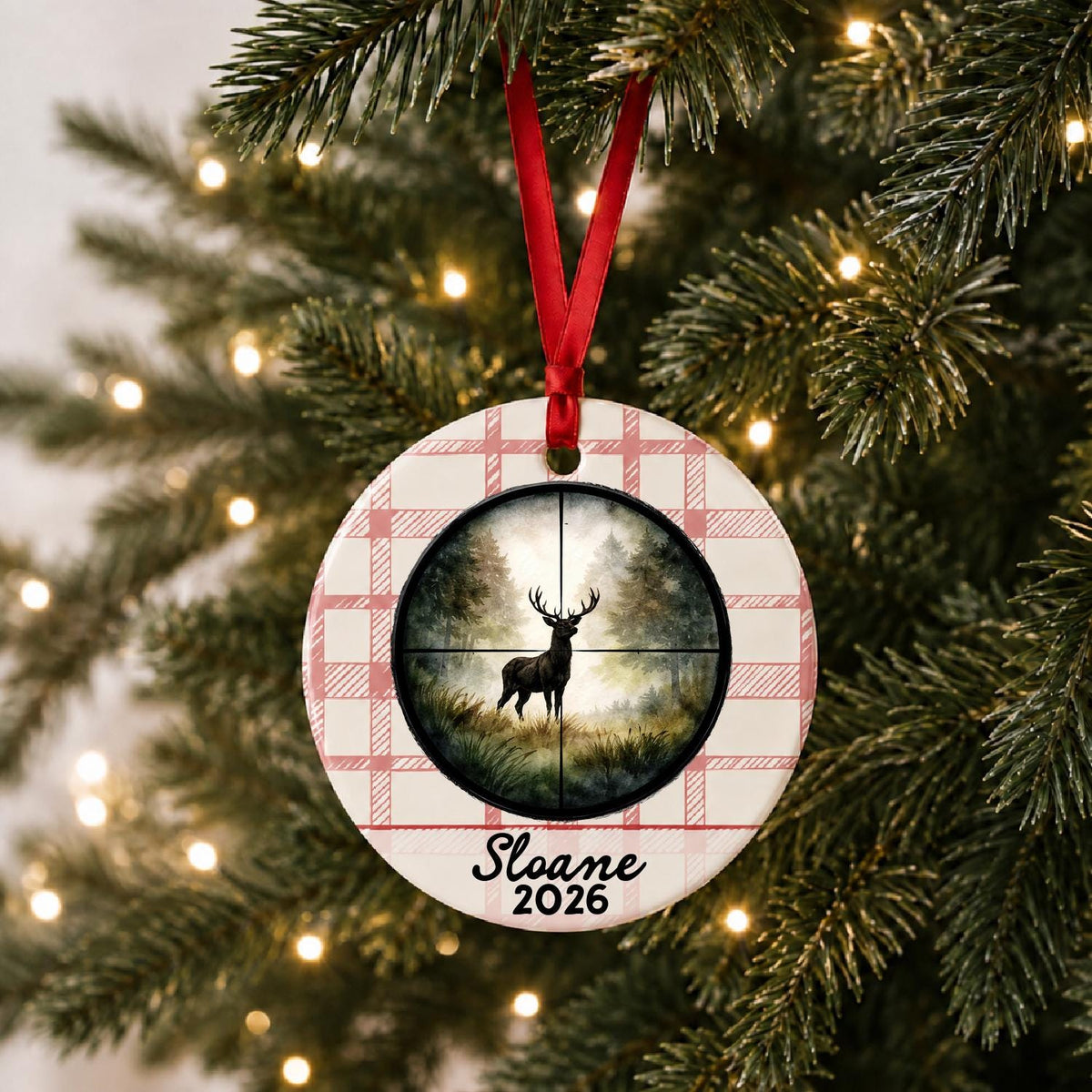 Personalized deer hunting ceramic ornament with name and year on red plaid hanging on a lit Christmas tree
