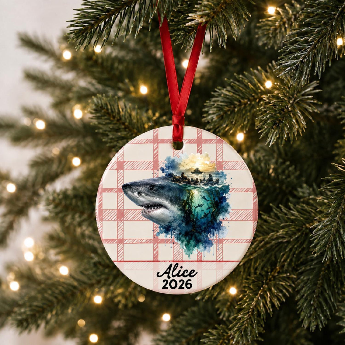 Personalized great white shark ceramic ornament with name and year on red plaid hanging on a lit Christmas tree
