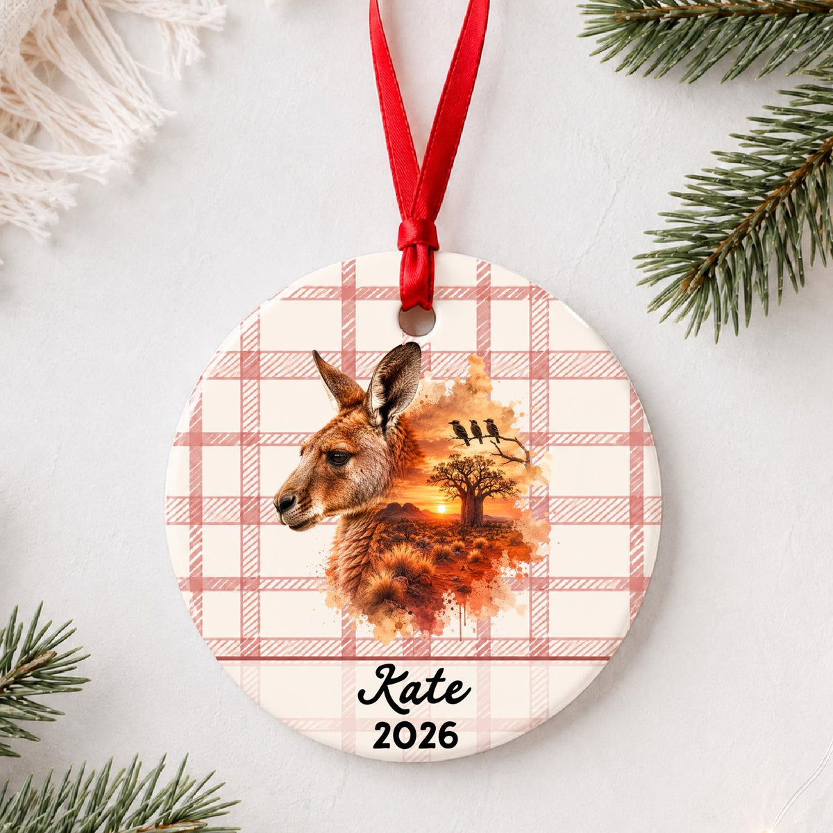 Personalized red kangaroo ceramic ornament with name and year on red plaid styled with pine branches on a soft white background