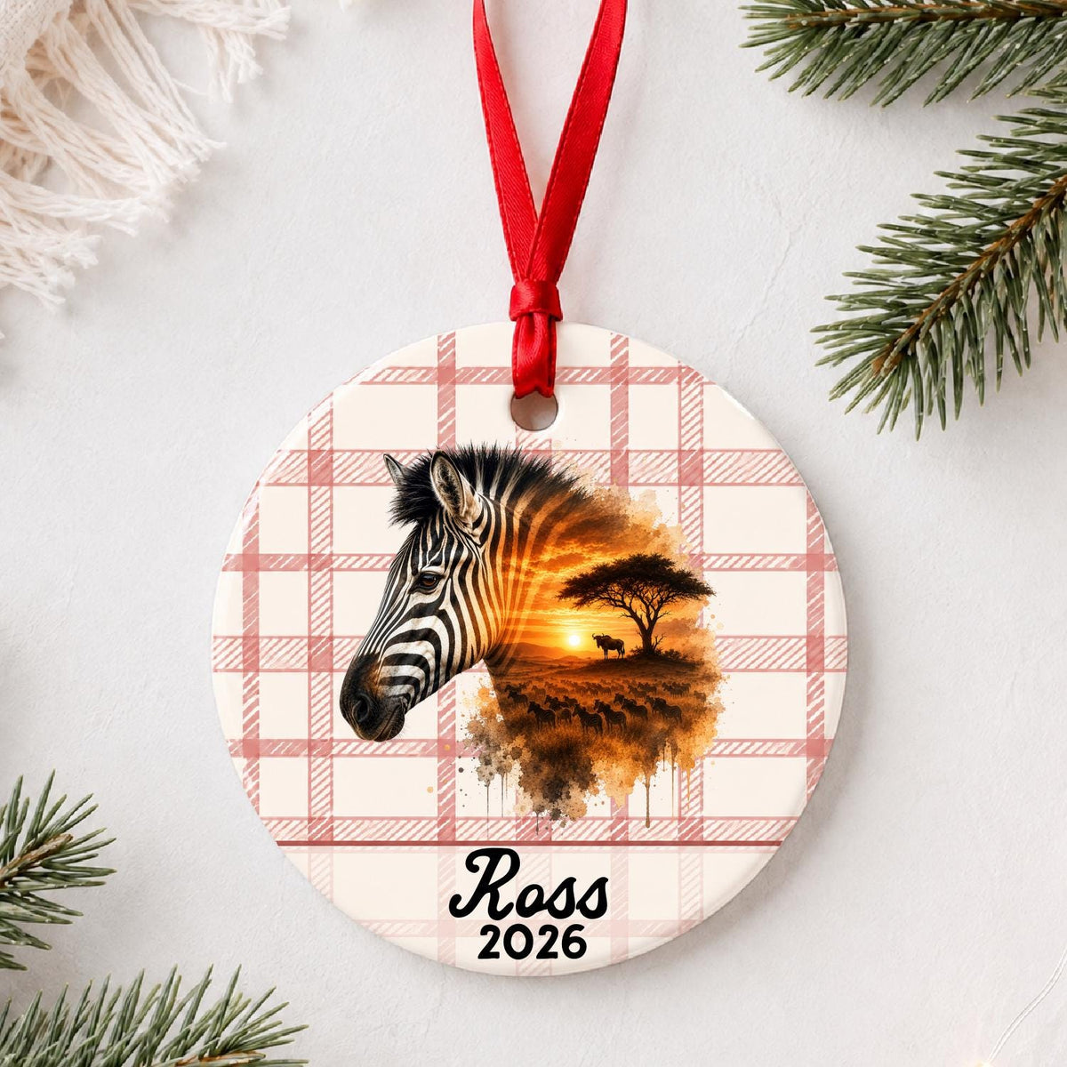 Personalized plains zebra ceramic ornament with name and year on red plaid styled with pine branches on a soft white background