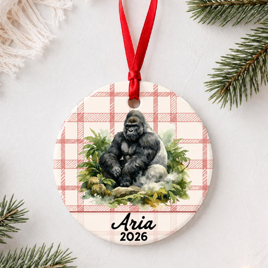 Personalized silverback gorilla ceramic ornament with name and year on red plaid styled with pine branches on a soft white background