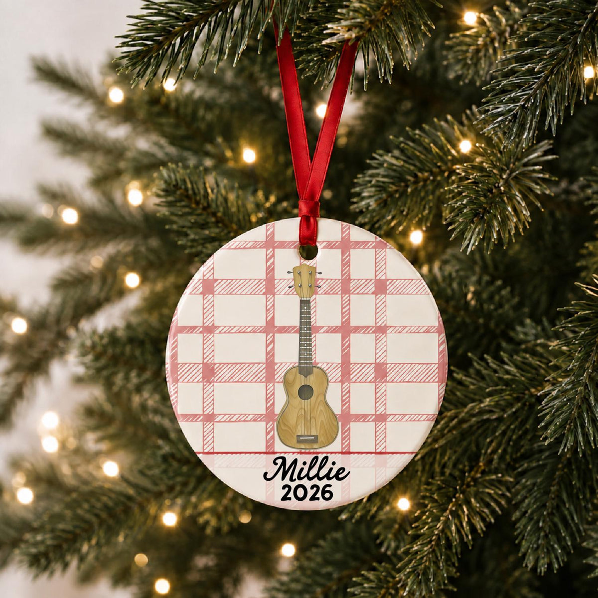 Personalized ukulele ceramic ornament with name and year on red plaid hanging on a lit Christmas tree