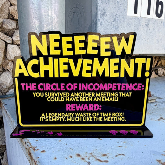Black freestanding New Achievement sign with yellow and pink lettering about surviving a meeting that could have been an email