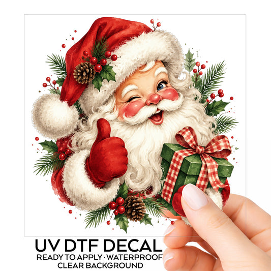 Winking Santa Claus With Gift UV DTF sticker on its backing card, held in hand