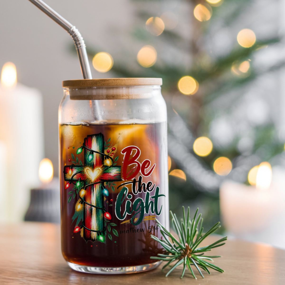 Be The Light Cross With Christmas Lights UV DTF sticker applied to a glass can cup of iced coffee with a straw