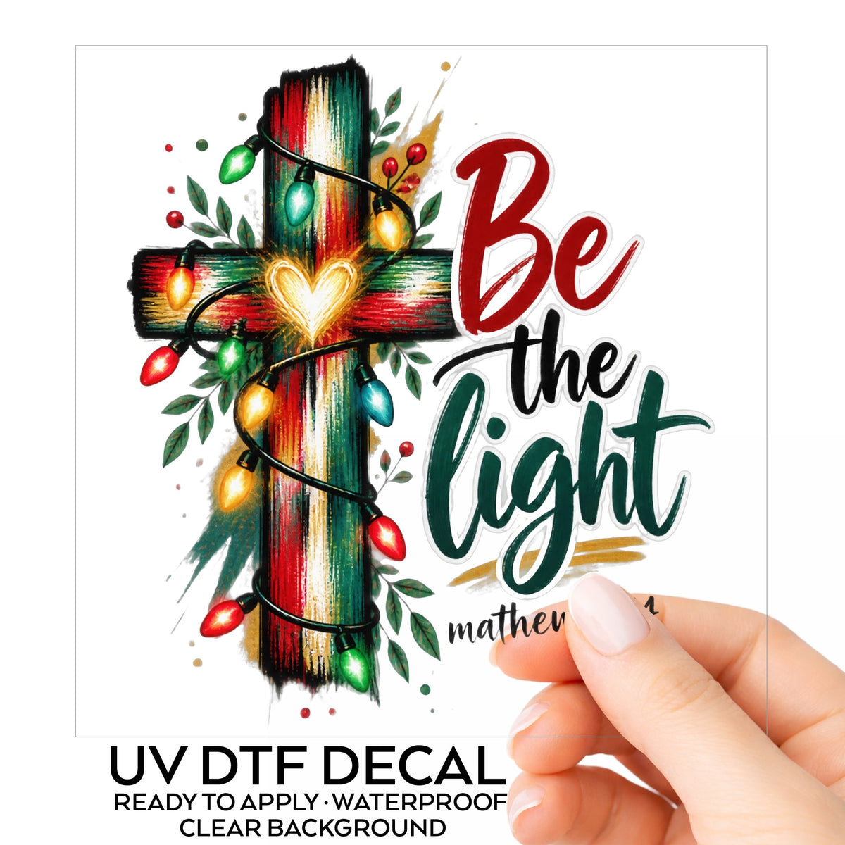 Be The Light Cross With Christmas Lights UV DTF sticker on its backing card, held in hand