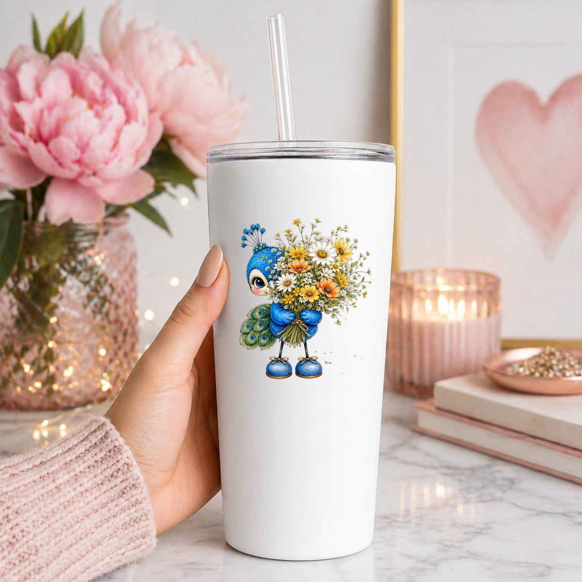 Peacock Holding Wildflower Bouquet UV DTF sticker applied to a white straw tumbler beside pink peonies