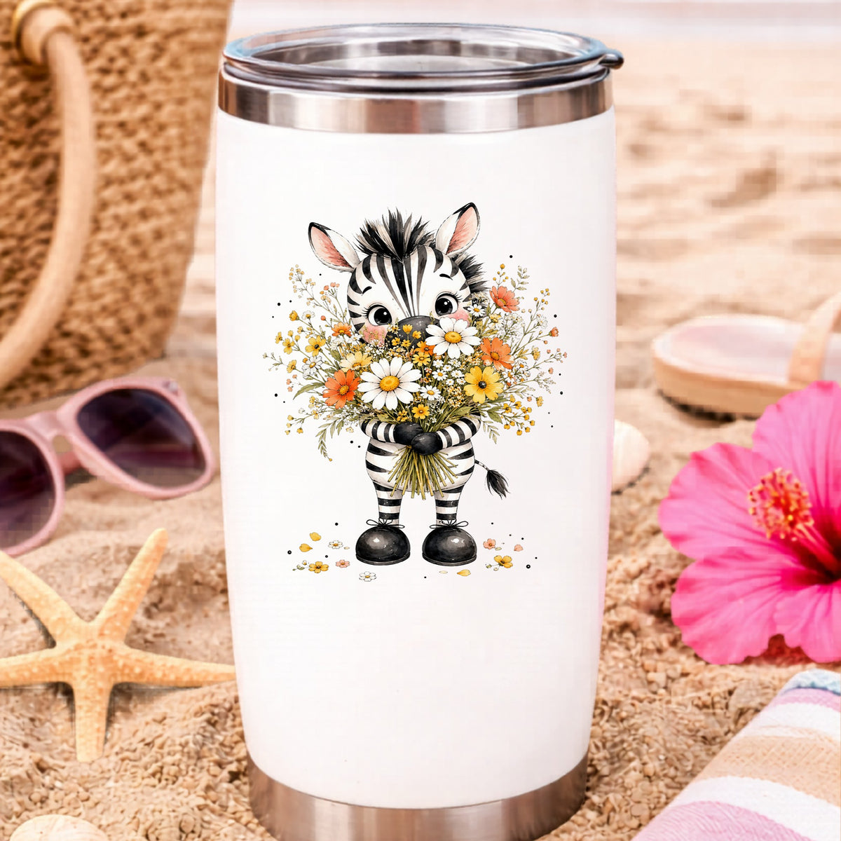 Zebra Holding Wildflower Bouquet UV DTF sticker applied to a white travel tumbler on beach sand