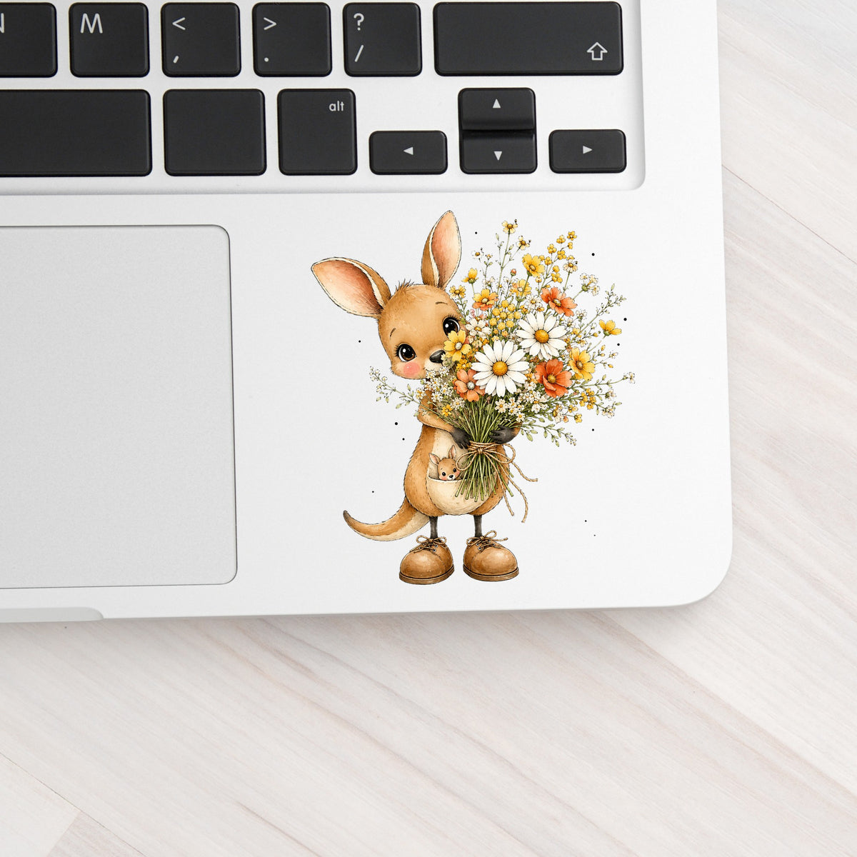Kangaroo Holding Daisy Bouquet UV DTF sticker applied to a silver laptop beside the keyboard