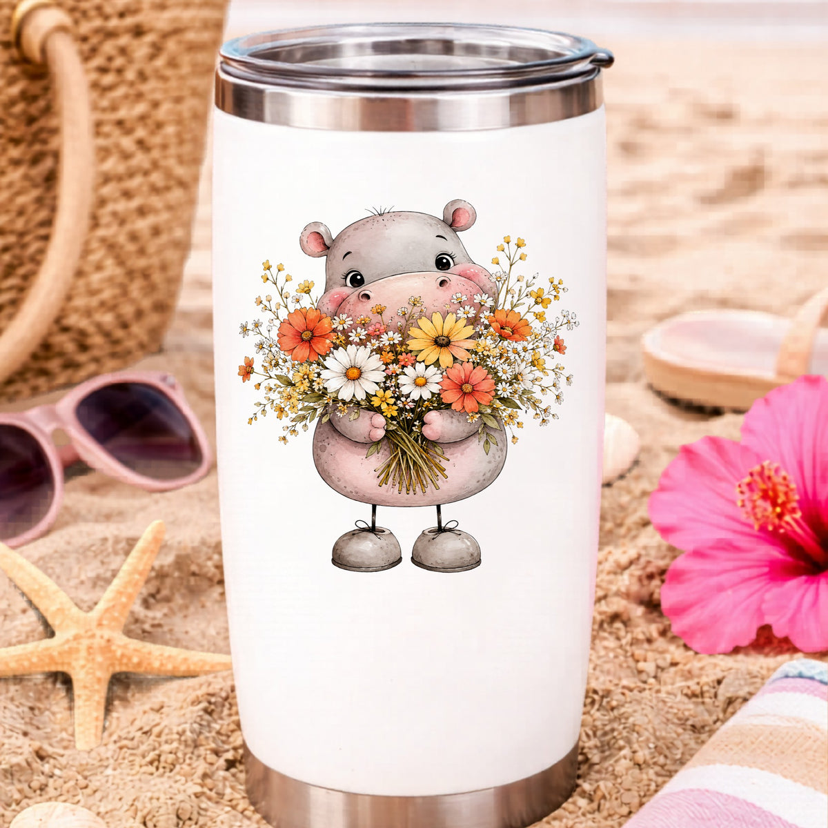 Pink Hippo Holding Wildflower Bouquet UV DTF sticker applied to a white travel tumbler on beach sand