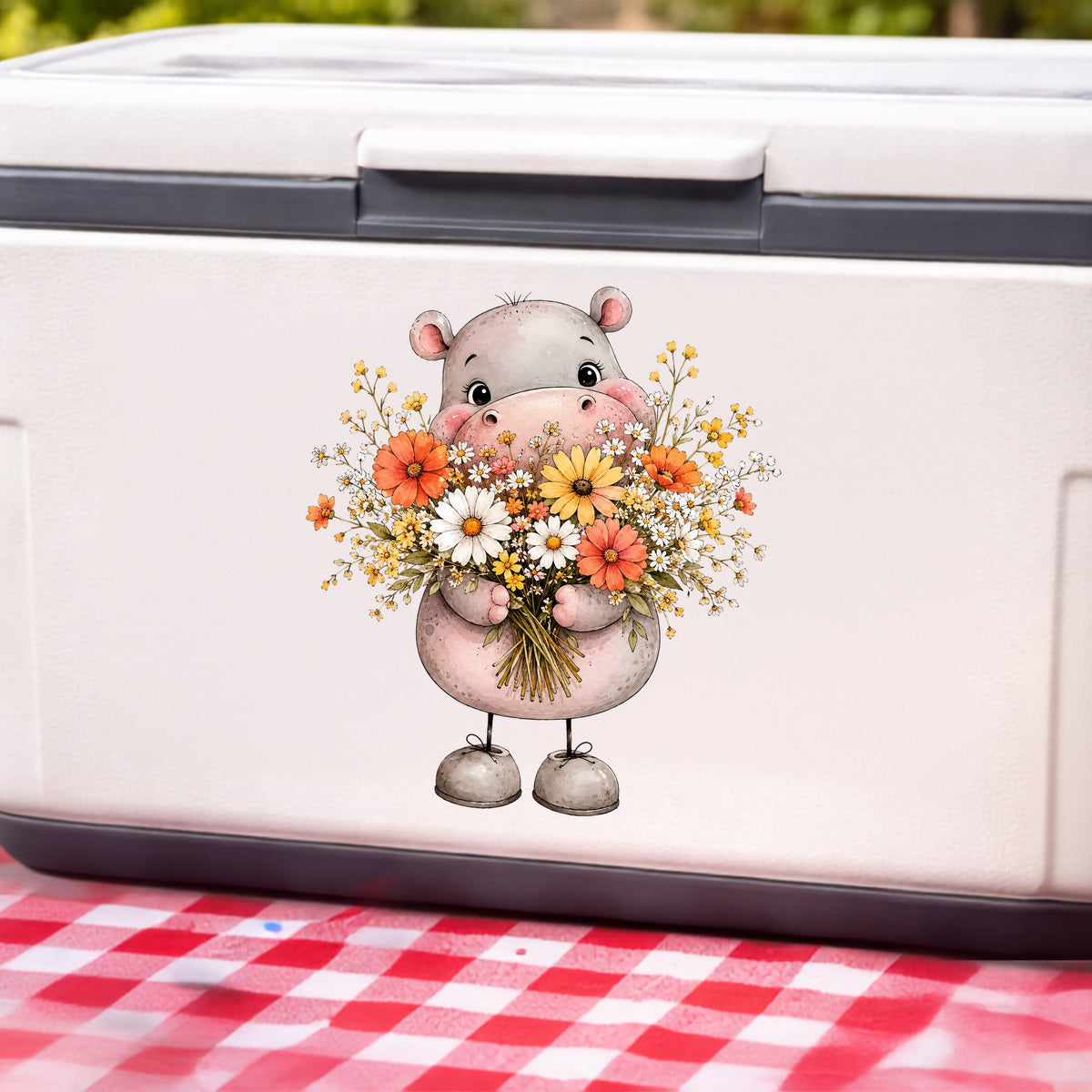 Pink Hippo Holding Wildflower Bouquet UV DTF sticker applied to a white cooler on a red gingham cloth