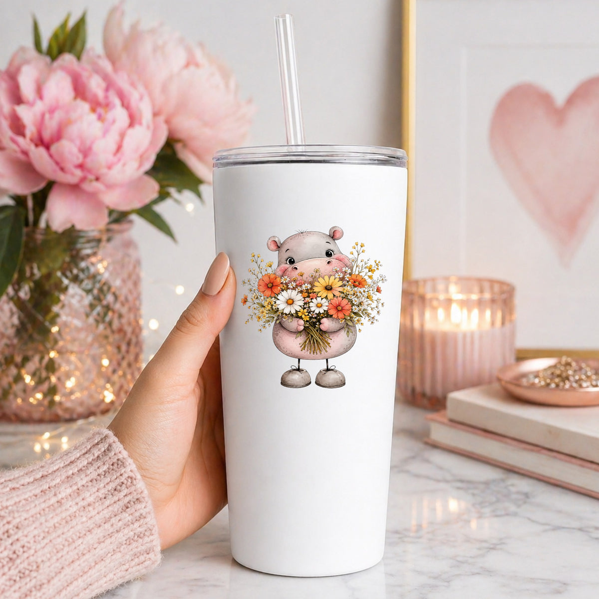 Pink Hippo Holding Wildflower Bouquet UV DTF sticker applied to a white straw tumbler beside pink peonies