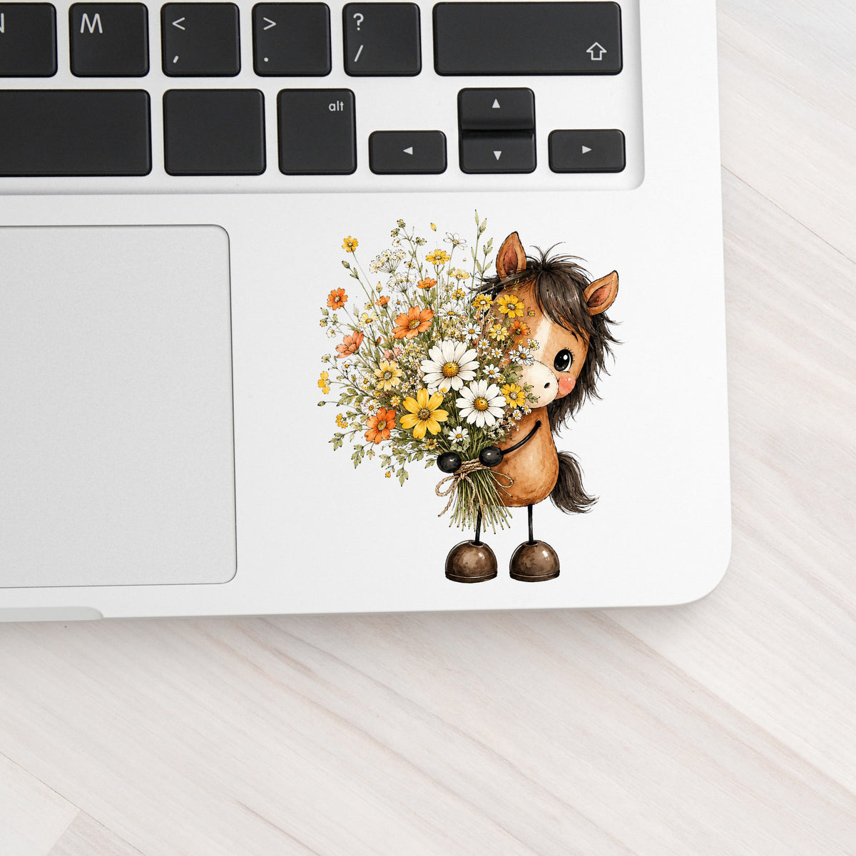 Brown Horse Holding Wildflower Bouquet UV DTF sticker applied to a silver laptop beside the keyboard