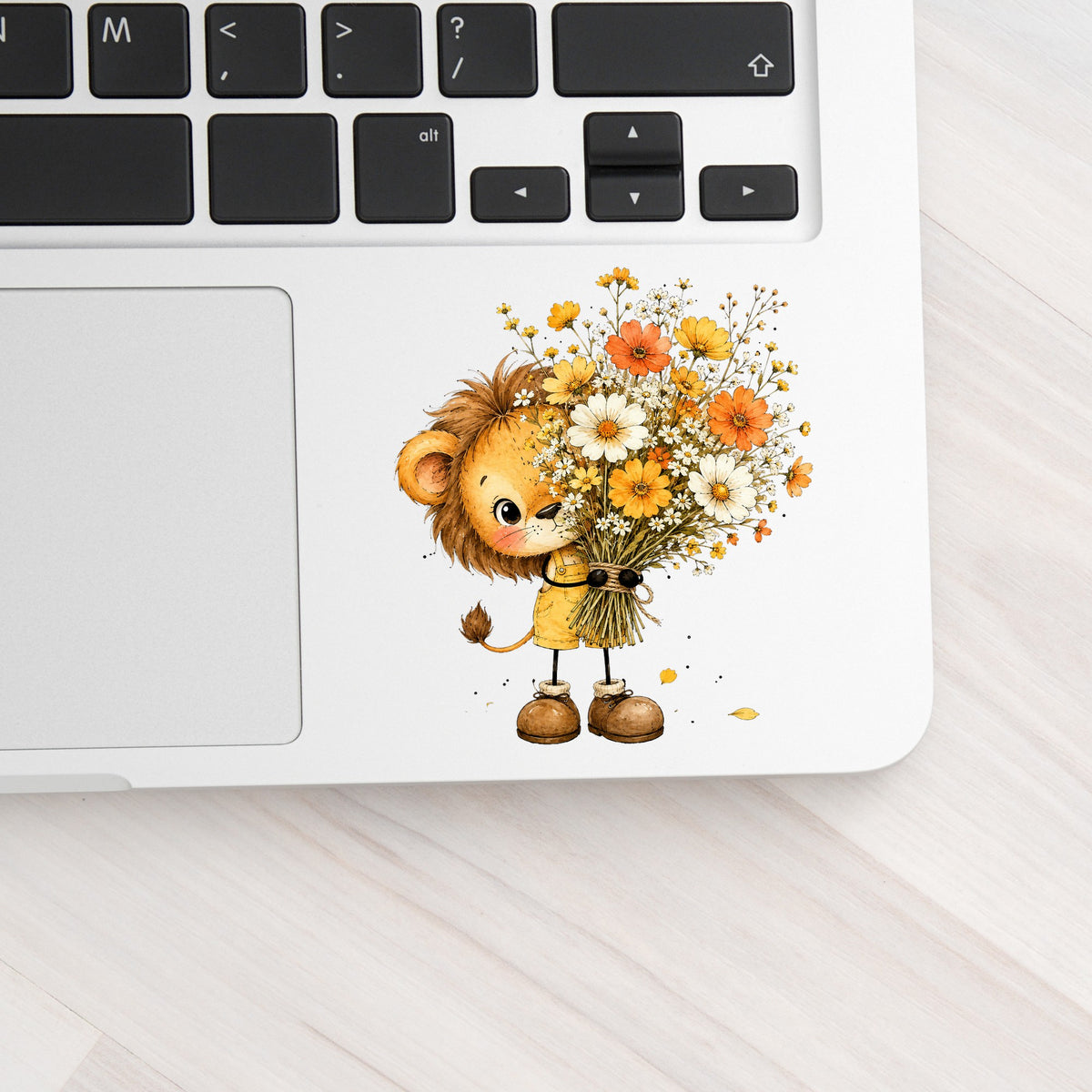 Baby Lion Holding Wildflower Bouquet UV DTF sticker applied to a silver laptop beside the keyboard