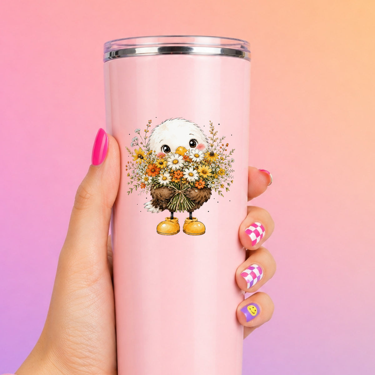 Baby Eagle Holding Daisy Bouquet UV DTF sticker applied to a tall pink tumbler on a pink and orange background