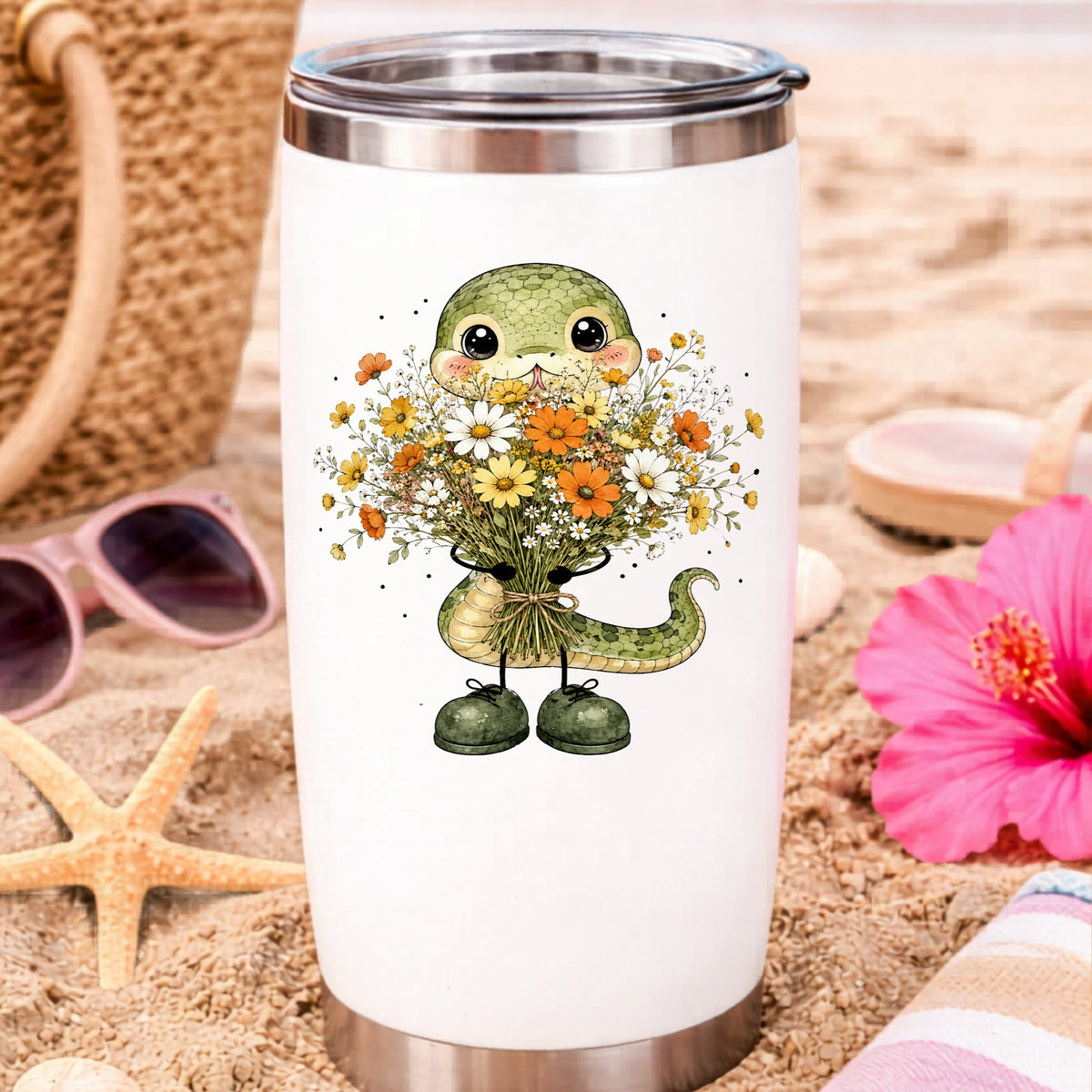 Green Snake Holding Wildflower Bouquet UV DTF sticker applied to a white travel tumbler on beach sand