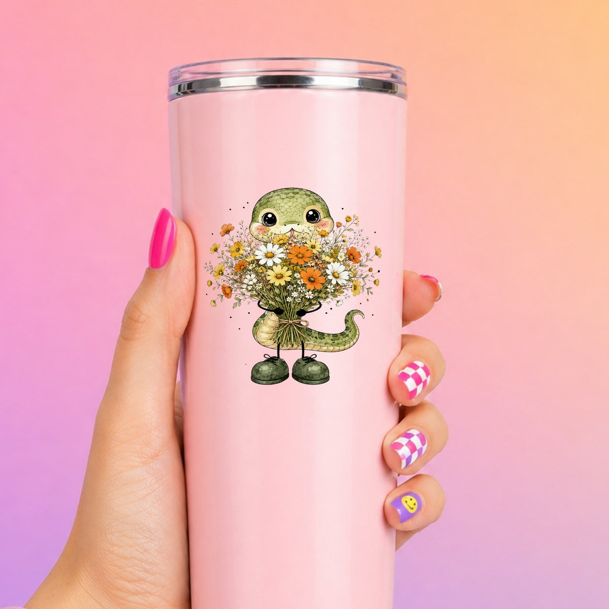 Green Snake Holding Wildflower Bouquet UV DTF sticker applied to a tall pink tumbler on a pink and orange background